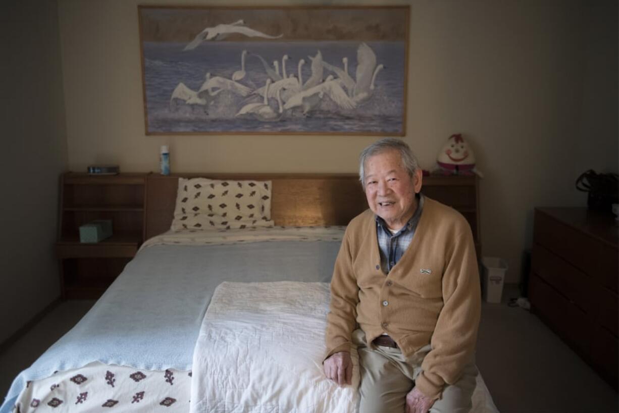 Ian Fujisaki poses for a photo under a painting he completed in 1999 at his Vancouver home. As a teenager, Fujisaki lived on Hawaii during the U.S. military occupation after the attack on Pearl Harbor.