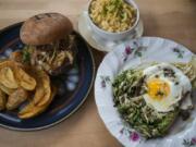 A hamburger, from left, is served with mac ‘n’ cheese as well as the grilled romaine at The Grocery Cocktail & Social.