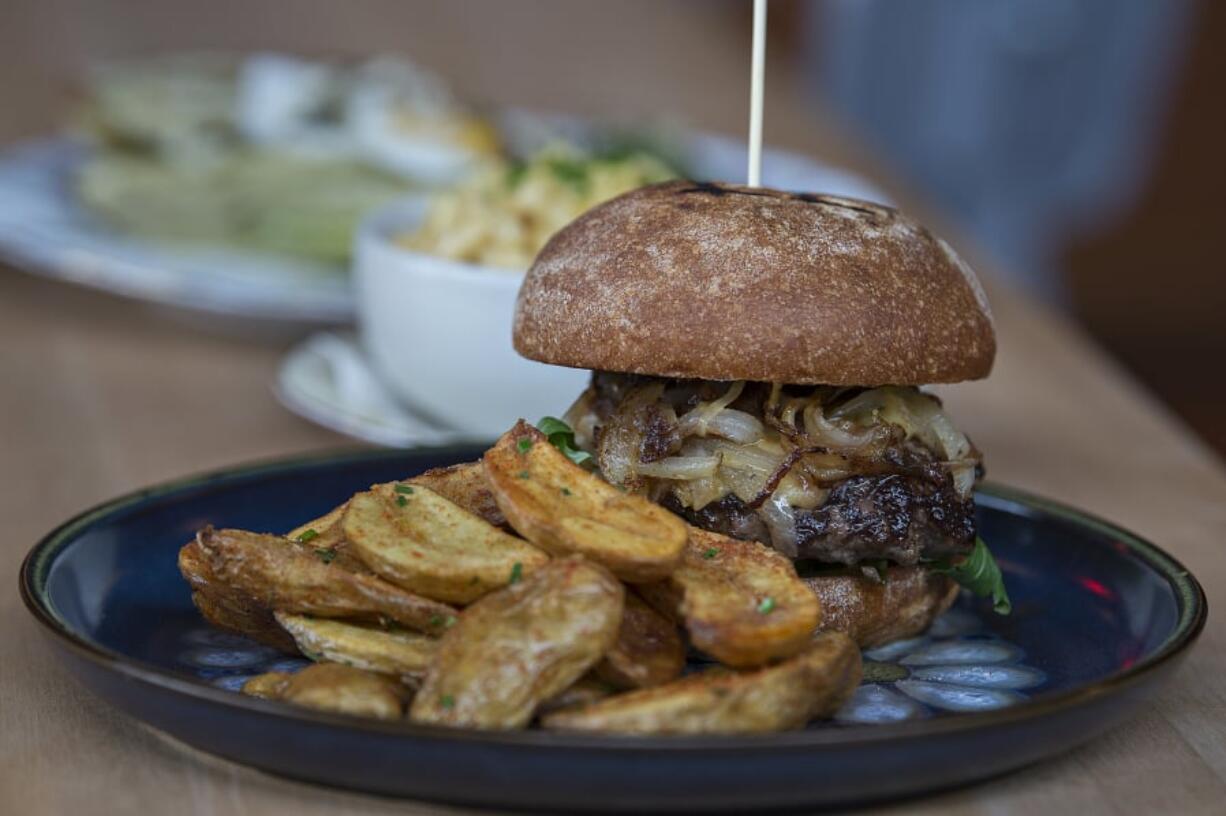 A hamburger, front to back, is served with mac ‘n’ cheese.