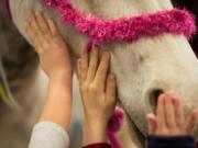 Children pet Shelby, a horse dressed like a unicorn, during the last day of the Washington State Horse Expo.