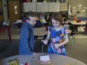 Anthony Moro-Baxter, 10, left, a former student at South Ridge Elementary School, offers encouragement as he stops by the work station of first-grader Delaney Baylous, 7, while she creates a card that will be given to a patient at Randall Children’s Hospital in Portland.