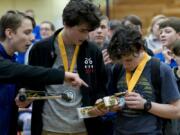 Nate McConnell, from left, interacts with classmates Aran O’Day and Mason McCarty as the teammates study their second-place trophy during the Solar Car Challenge at Hudson’s Bay High School Saturday in Vancouver. The challenge is a mixture of a science fair and pinewood derby, where teams present their car designs and race.