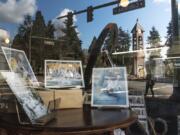 The reflection of Esther Short Park is seen in the window of Geme Art on Wednesday.