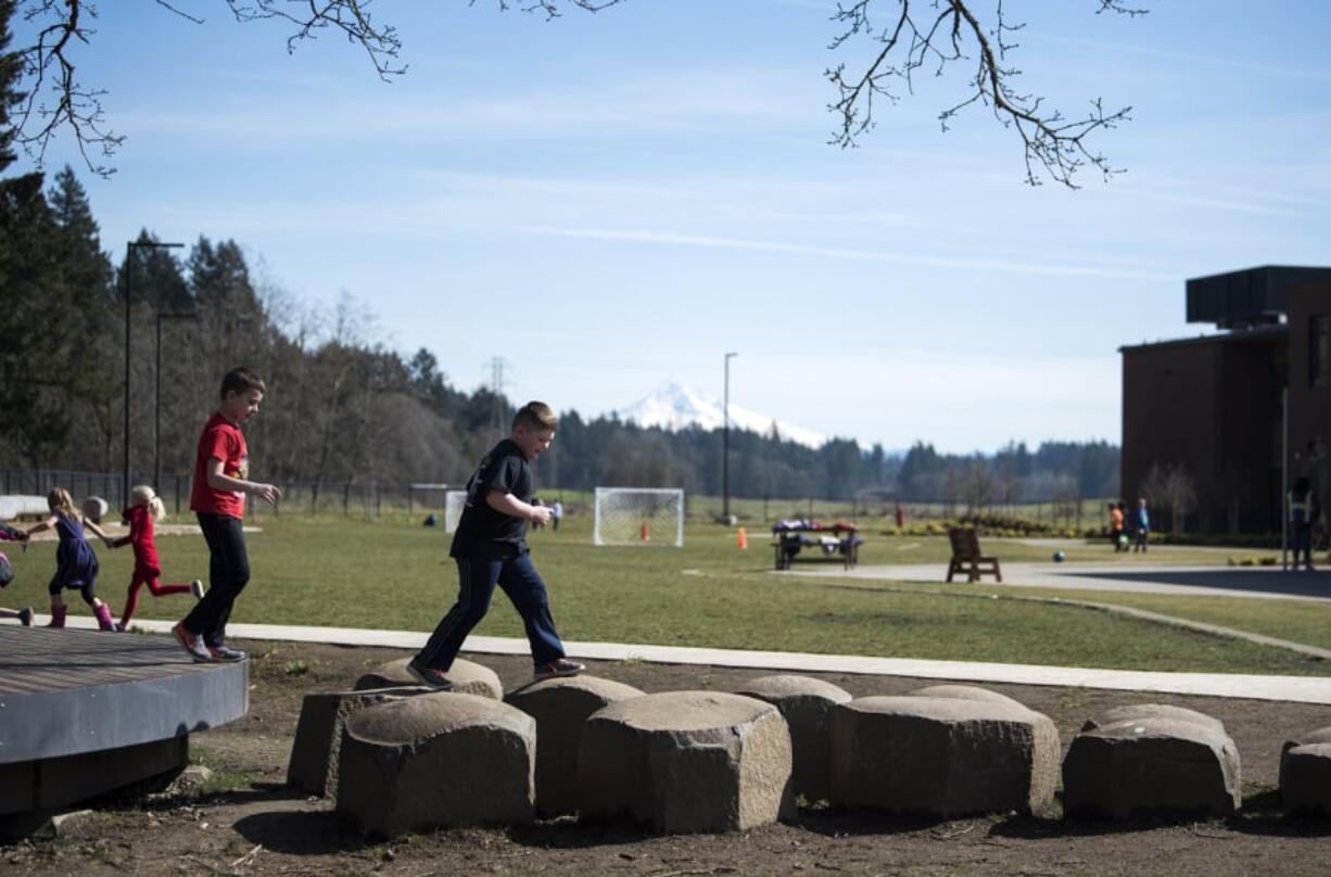 Lacamas Lake Elementary School second-grader Owen Query, left, and Mason Krause, right, run along the natural play elements outside of the first-year school, which was opened to deal with increasing enrollment and more development moving north of Lacamas Lake. The district passed a 2016 bond to build the school, but changes in the state education funding model have created difficulties for schools in Washington. Camas is facing an $8.2 million shortfall for the upcoming school year and might have to make reductions to even out the budget.