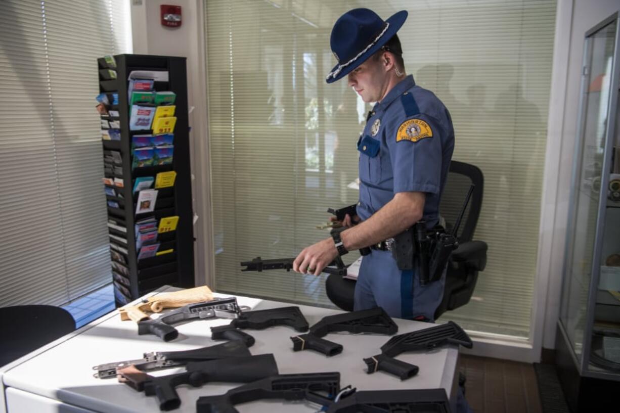 Trooper Shane Kesler lays out bump stocks that have been collected during a bump stock buyback event hosted by Washington State Patrol in Vancouver. Leading up to the federal ban that takes effect on March 26, owners of bump stocks can turn them in to the Washington State Patrol for a $150 each.