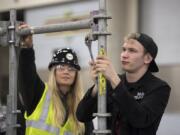 Lisa Marx of Northwest Carpenters Institute of Washington, left, looks on as a Deric Goodwin, 18, of Camas High School learns how to erect scaffolding during the Youth Employment Summit in Ridgefield. Workforce Southwest Washington gathered representatives from 60 businesses to talk with around 600 high school age youth from Clark and Cowlitz counties during the event.