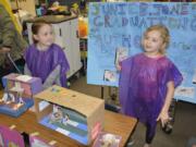 Washougal: Gause Elementary School first-graders Myah White, left, and Hailey Faught with their posters and dioramas for the school’s book party.