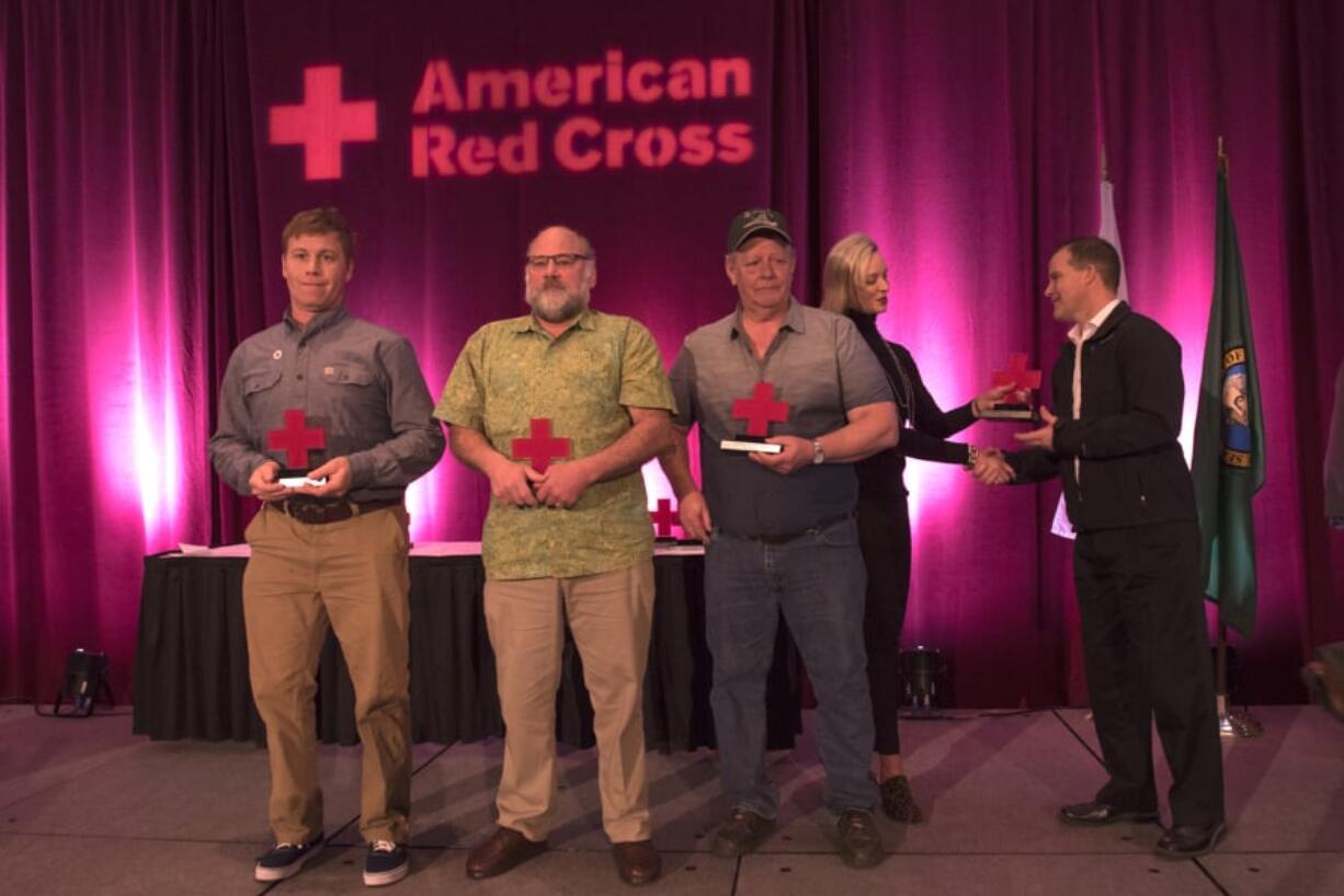 Tug Pilot Riley Wyatt, from left, deck mechanic Harry Pike and deck mechanic Ken Marvel display their Good Samaritan awards as Kelly Schrader with IQ Credit Union hands the final award to Capt. Joshua Burrows during the Red Cross Heroes Breakfast. The crew saved a couple whose boat had overturned in Columbia River.