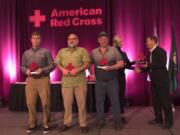 Tug Pilot Riley Wyatt, from left, deck mechanic Harry Pike and deck mechanic Ken Marvel display their Good Samaritan awards as Kelly Schrader with IQ Credit Union hands the final award to Capt. Joshua Burrows during the Red Cross Heroes Breakfast. The crew saved a couple whose boat had overturned in Columbia River.