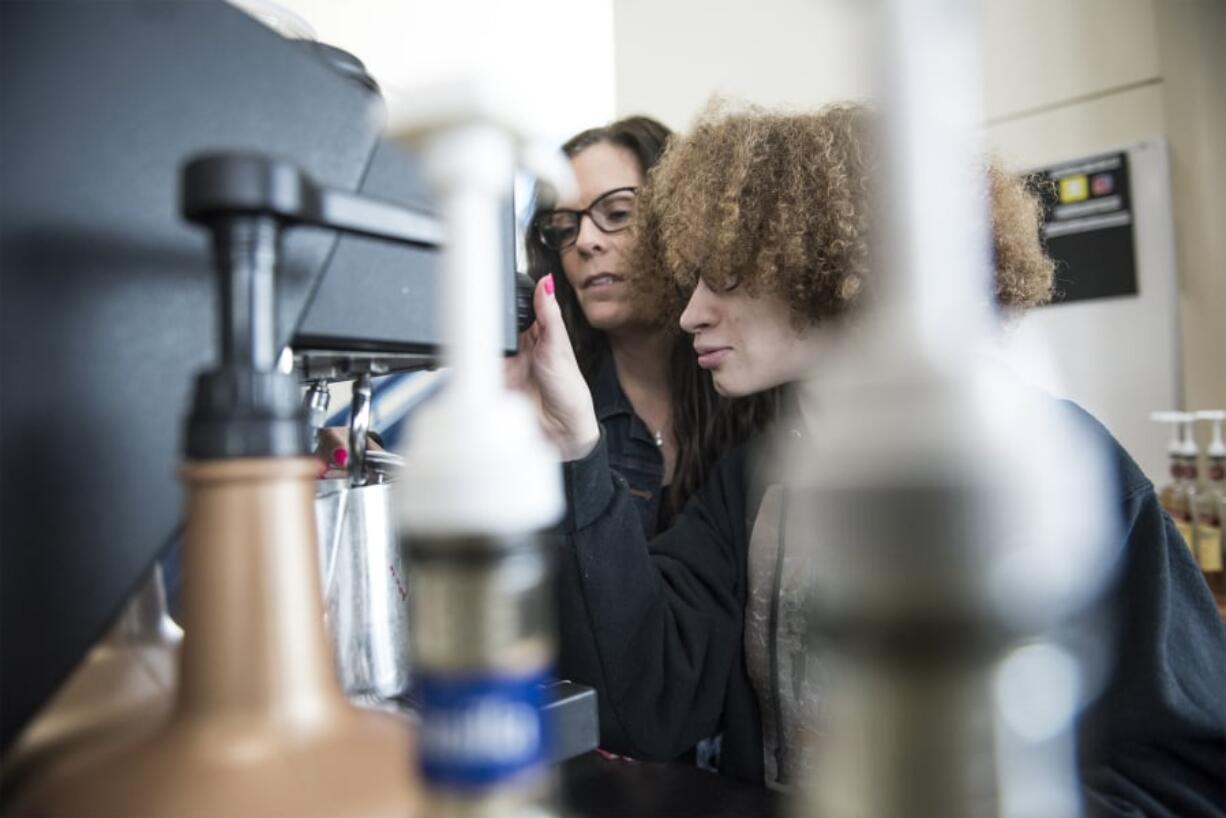 Hockinson High School paraeducator Angela Stanek, left, helps Natalie Zapata, 19, with a coffee order while working at the school’s coffee cart, which is run by the 18-21 transition program. Stanek is one of two paraeducators for the program, which has six students this year, and is expected to grow next school year.