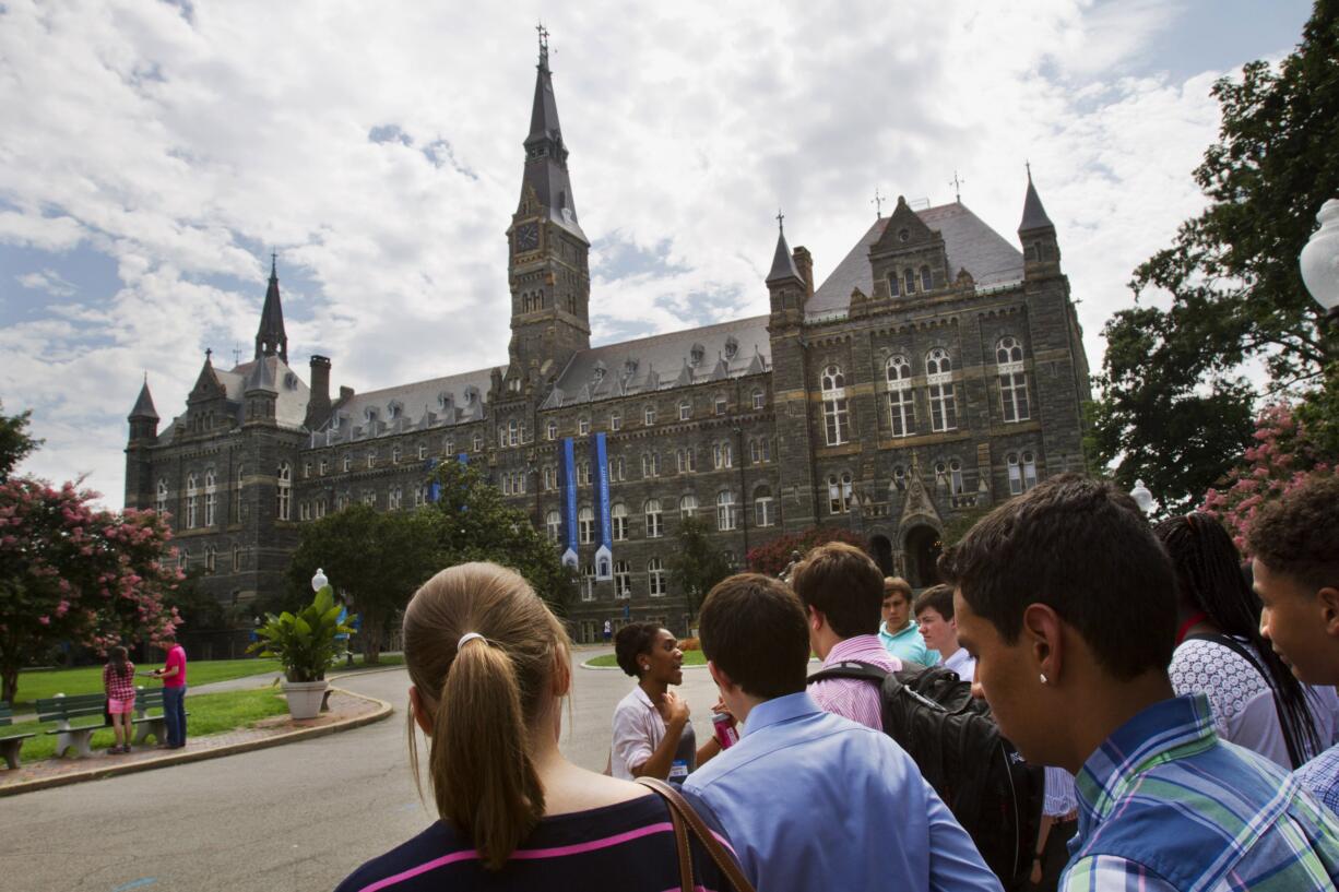 FILE - In this July 10, 2013, file photo, prospective students tour Georgetown University's campus in Washington. Federal authorities have charged college coaches and others in a sweeping admissions bribery case in federal court. The racketeering conspiracy charges were unsealed Tuesday, March 12, 2019, against the coaches at schools including Georgetown, Wake Forest University and the University of Southern California. Authorities say the coaches accepted bribes in exchange for admitting students as athletes, regardless of their ability.