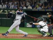 Seattle Mariners' Domingo Santana hits a grand slam off Oakland Athletics starter Mike Fiers in the third inning of Game 1 of their Major League opening series baseball game at Tokyo Dome in Tokyo, Wednesday, March 20, 2019. Athletics catcher is catcher Nick Hundley.