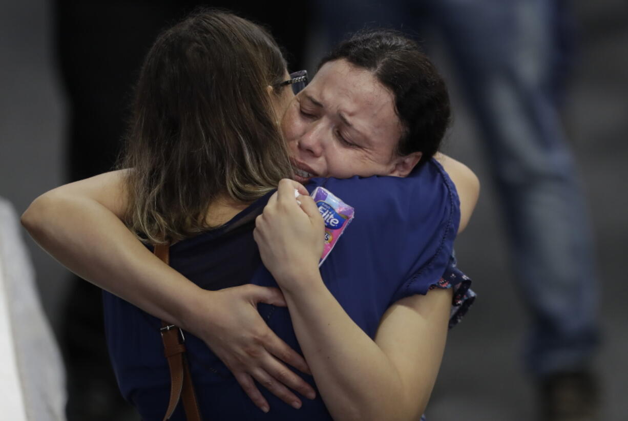 Relatives embrace during a collective wake of the victims of the shooting at the Raul Brasil State School in Suzano, greater Sao Paulo area, Brazil, Thursday, March 14, 2019. The Sao Paulo suburb prepares to bury its dead and look for reasons why two masked former students armed with a hand gun, knives, axes and crossbows killed five teenagers and two adults at a school before killing themselves as police closed in.