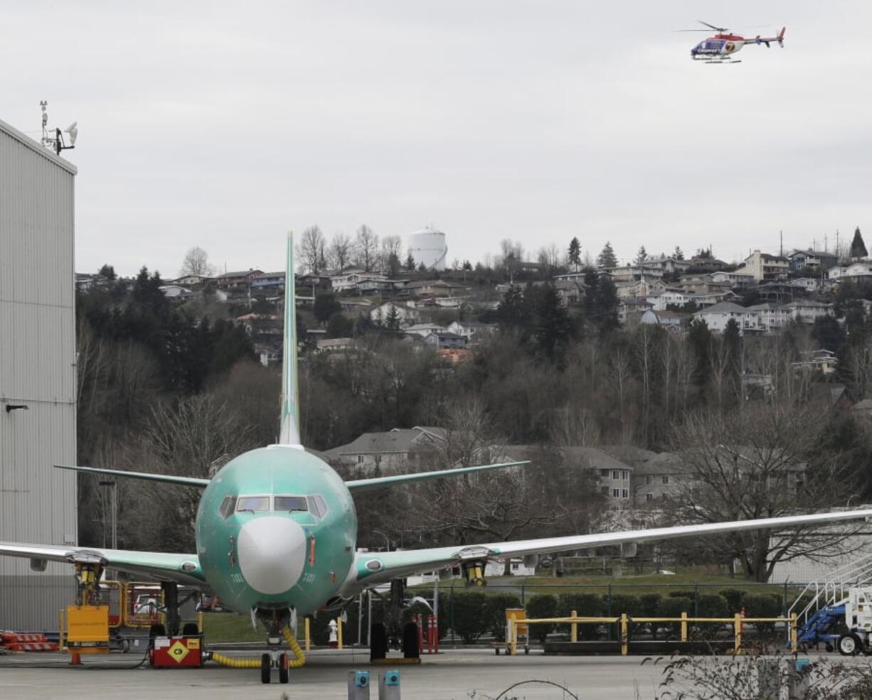 A TV news helicopter flies above a Boeing 737 MAX 8 airplane parked at Boeing Co.’s Renton Assembly Plant on Monday in Renton. Ted S.