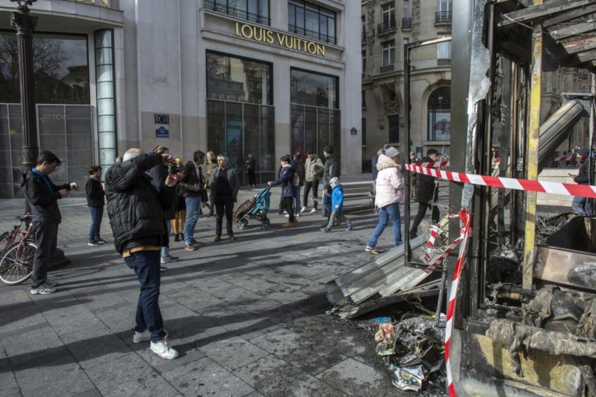 Bystanders take snapshots of the damage at the famed restaurant Le Fouquet’s on the Champs Elysees on Sunday the day after it was vandalized and set on fire during the 18th straight weekend of demonstrations by the yellow vests, in Paris.