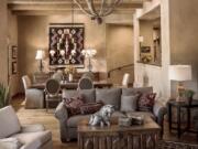 The combination living-dining room in a Santa Fe home in the mountains in Tucson, Ariz. The home was remodeled with chestnut board floors, hand-applied plaster, viga-style beams, and furnishings including a wood trunk from South America, a pair of antique iron lamps made from a reclaimed balcony rail from Spain, two antique Navajo rugs and a collection of old pueblo pottery and antique Apache baskets.