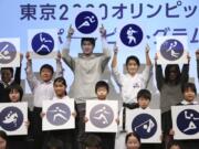 Rio Olympics athletics silver medallist Shota Iizuka, top center left, karate athlete Kiyo Shimizu, top center right, and elementary school students pose with pictograms of Tokyo 2020 Olympic sports events during a celebration to mark 500 days to go, in Tokyo, Tuesday, March 12, 2019. Organizers marked the milestone on Tuesday, unveiling the stylized pictogram figures for next year’s Tokyo Olympics.