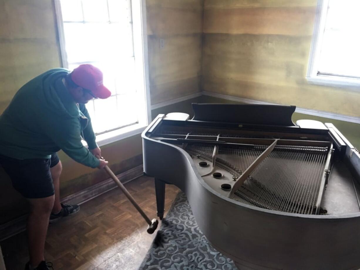 Artist Aaron Angelo takes a sledgehammer to the leg of a baby grand piano in a house where two rooms are being transformed to look as they might have looked once floodwaters receded following Hurricane Katrina in New Orleans. The house sits in front of one of the flood walls that failed when Katrina hit nearly 14 years ago. The nonprofit group Levees.org bought the house and is transforming it as part of its effort to educate the public on the causes of the 2005 flood.