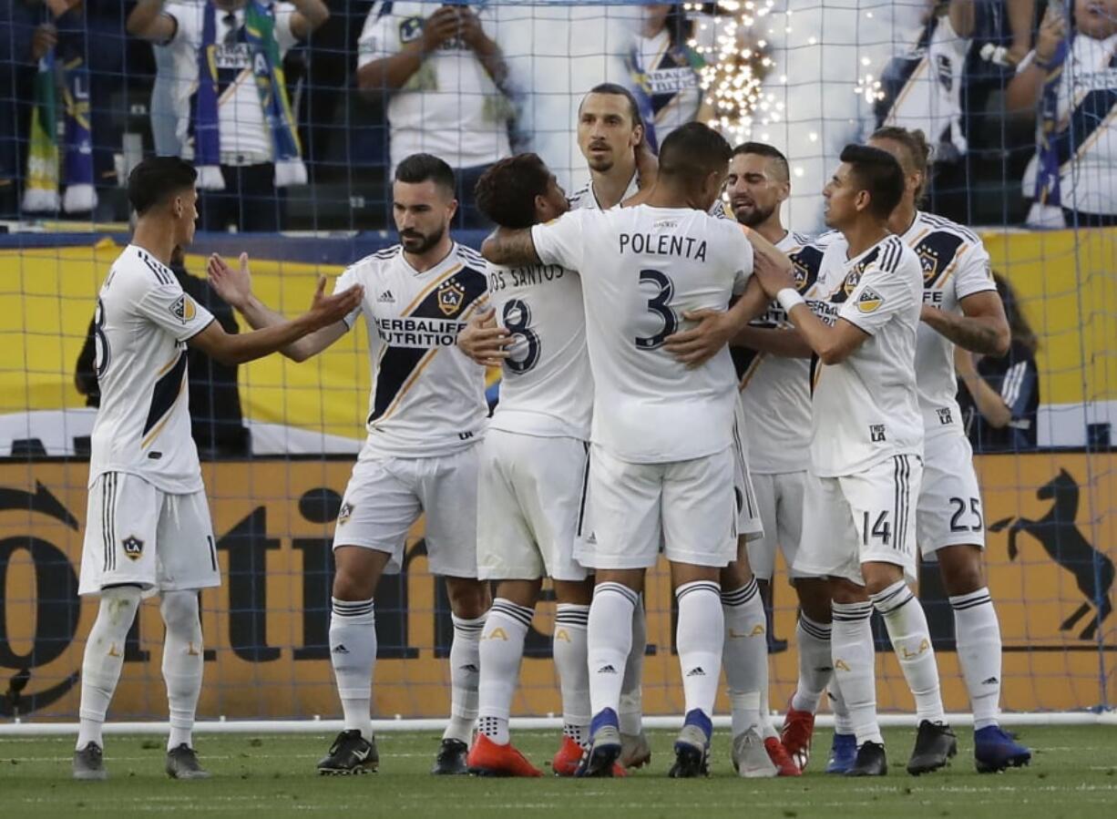 Los Angeles Galaxy forward Zlatan Ibrahimovic, center, is hugged by teammates after scoring against the Portland Timbers during the first half of an MLS soccer match Sunday, March 31, 2019, in Carson, Calif.