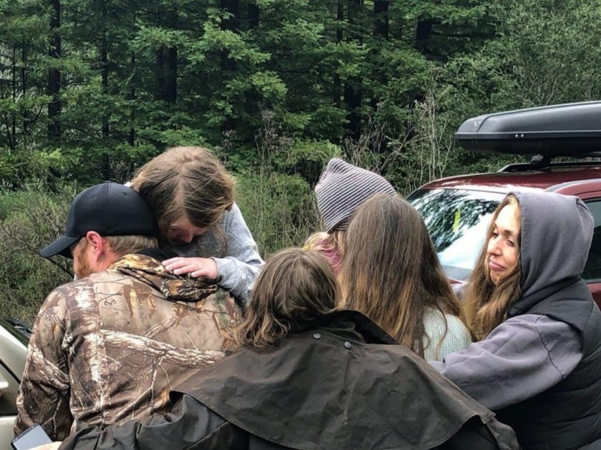 In this Sunday, March 3, 2019 photo provided by the Humboldt County Sheriff’s Office rescuers and family members comfort Leia, back left, and Caroline Carrico, back right, after they were found near Benbow, Calif. Armed with some outdoor survival training, granola bars and pink rubber boots, the 5- and 8-year-old sisters survived 44 hours in the rugged Northern California wilderness before they were found dehydrated and cold but in good spirits on Sunday, authorities said.