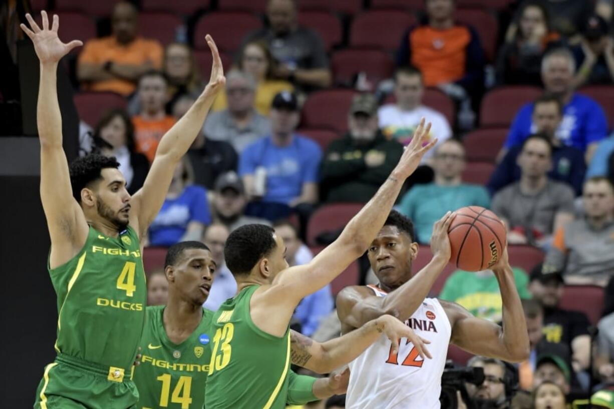 Virginia’s De’Andre Hunter (12) is defended by Oregon’s Ehab Amin (4), Kenny Wooten (14) and Paul White (13) during the first half of a men’s NCAA Tournament college basketball South Regional semifinal game, Thursday, March 28, 2019, in Louisville, Ky. (AP Photo/Timothy D.