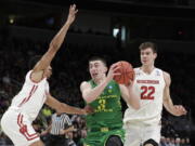 Oregon guard Payton Pritchard (3) drives between Wisconsin guard D’Mitrik Trice, left, and forward Ethan Happ (22) during the first half of a first-round game in the NCAA men’Äôs college basketball tournament Friday, March 22, 2019, in San Jose, Calif.