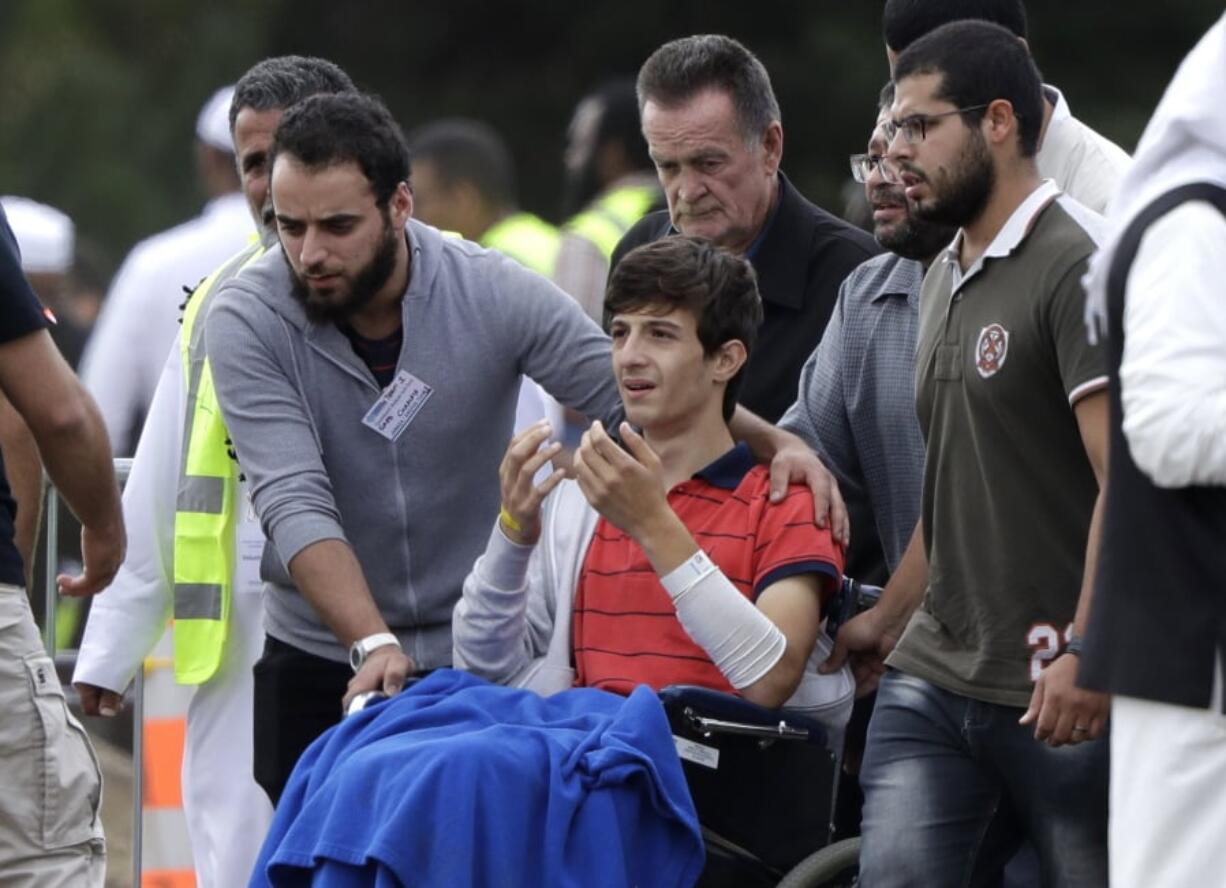 Zaed Mustafa, in wheelchair, brother of Hamza and son of Khalid Mustafa killed in the Friday, March 15 mosque shootings reacts during their burial at the Memorial Park Cemetery in Christchurch, New Zealand, Wednesday, March 20, 2019.