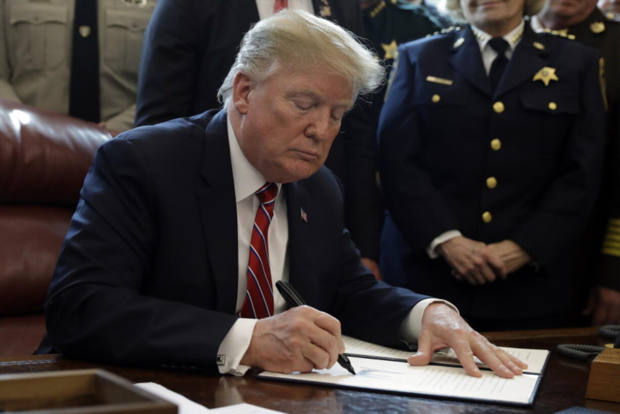 President Donald Trump signs the first veto of his presidency Friday in the Oval Office of the White House.