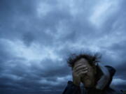 FILE - In this Friday, Sept. 14, 2018 file photo, Russ Lewis covers his eyes from a gust of wind and a blast of sand as Hurricane Florence approaches Myrtle Beach, S.C. According to a scientific report from the United Nations released on Wednesday, March 13, 2019, climate change, a global major extinction of animals and plants, a human population soaring toward 10 billion, degraded land, polluted air, and plastics, pesticides and hormone-changing chemicals in the water are making the planet an increasing unhealthy place for people.