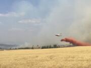 An air tanker drops retardant on a wheat field as crews battled an Eastern Washington wildfire last August.