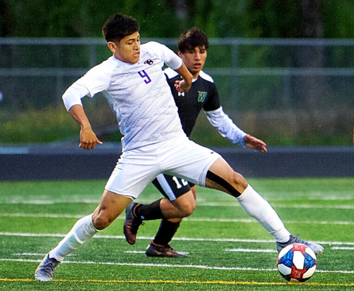 Coumbia River’s Aaron Espinosa (9) plays the ball in front of Woodland’s Anthony Clifford (12).