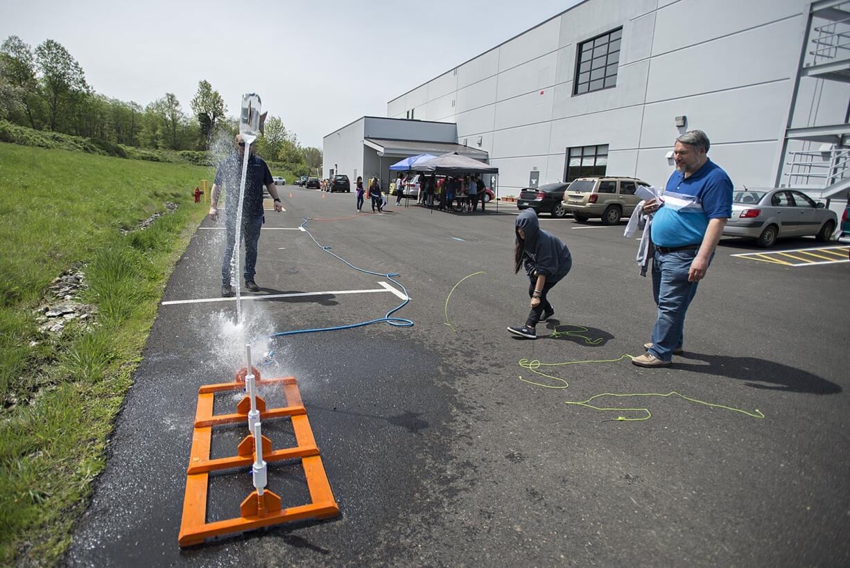 Rosalynn Bussiere, 11, in hoodie, takes her rocket filled with water for a test run while joined by her father, program manager Ron Bussiere, in blue, during Take Your Child To Work Day at Sigma Design in Camas on Thursday afternoon, April 25, 2019. The kids were challenged to build a rocket that could hold a cookie and keep it safe from launch through landing. In addition, participants in the event got a chance to learn how an idea goes from concept to production as well as play with trebuchet cookie catapults among other activities.