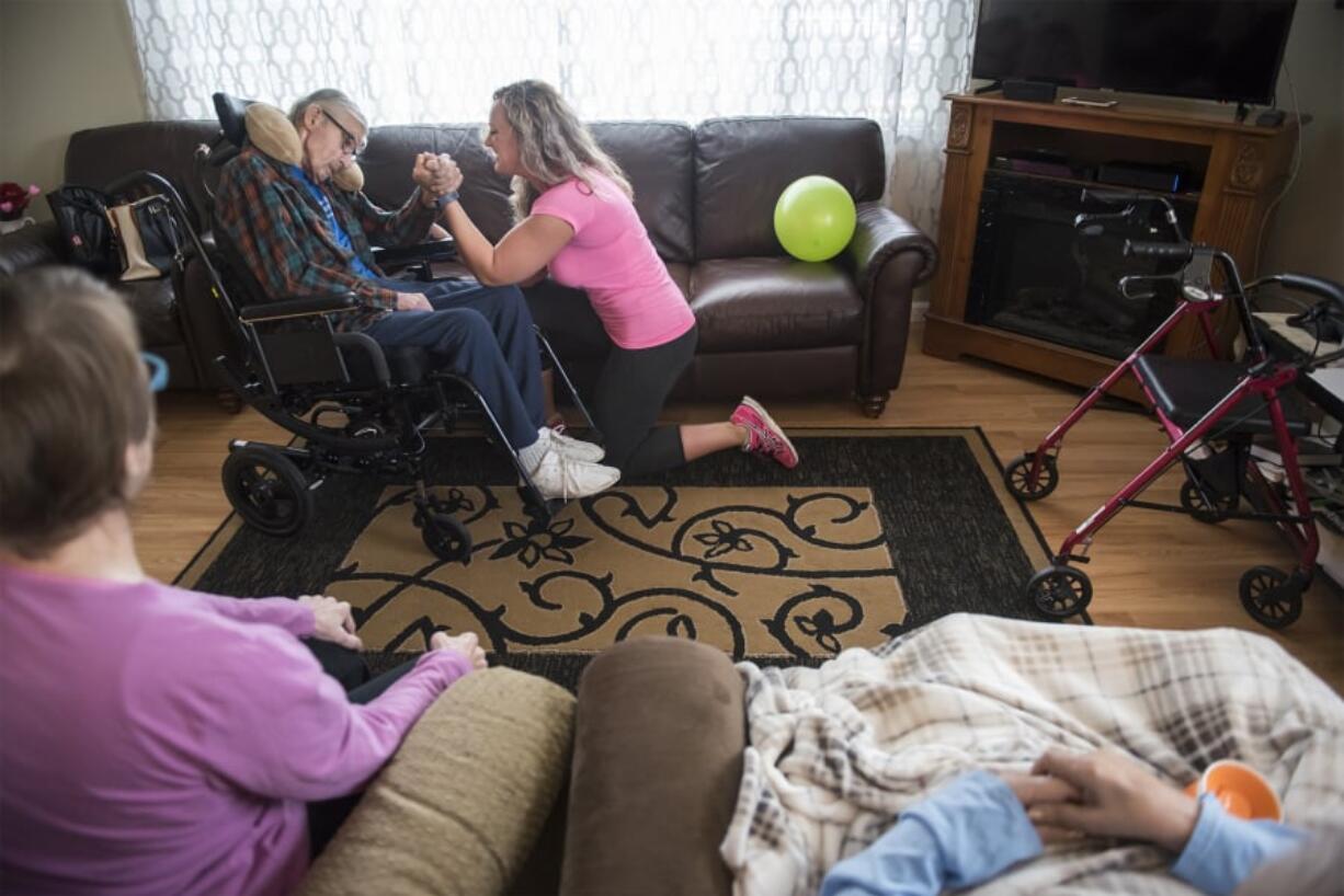 Dana Clelen, 65, foreground left, and Rita Ulrich, 81, foreground right, watch as Tauno Alanko, 99, and fitness trainer Mera Cosgrove work on resistance training during the Sit and Be Fit exercise class at Magda’s Adult Care in Vancouver. One resistance exercise Cosgrove performs with the residents is a gentle version of arm wrestling.