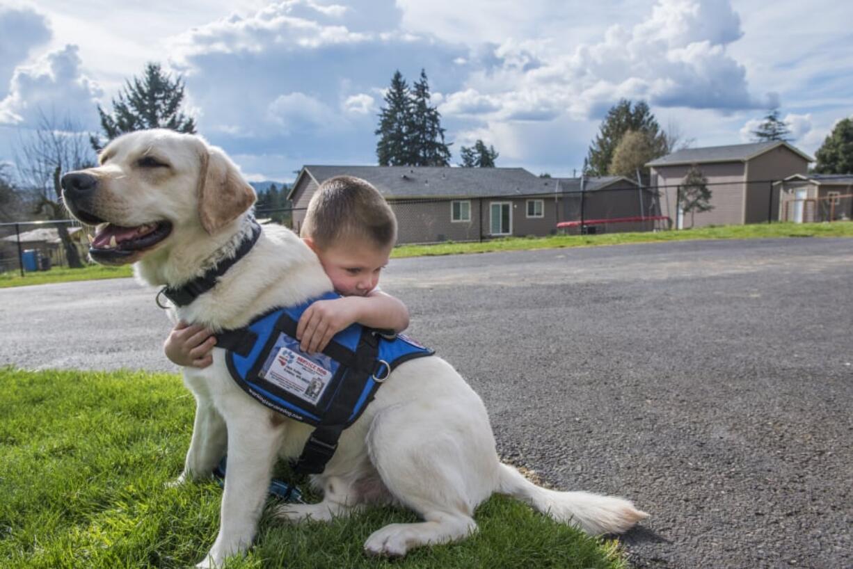 Jack Keller, 3, hugs his diabetic service dog Max in front of his home in Kalama. Max will paw Jack’s parents to alert them if Jack’s blood sugar enters dangerous territory.