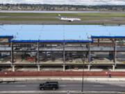 An Alaska Airlines jet taxis behind the Concourse E extension at Portland International Airport. The project, scheduled for completion in June 2020, is part of a $2 billion package of PDX improvements.