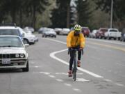 Cyclist Maurice Goudeau of Vancouver cruises past Clark College as he approaches the intersection of Fort Vancouver Way and McLoughlin Boulevard in the bike lane last week. At top, a sign near Clark College offers directions for people on two wheels as well as four.