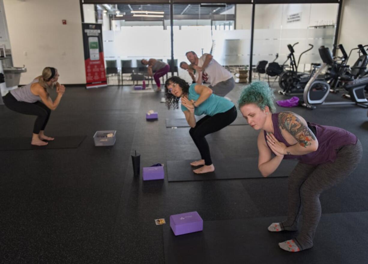 Yoga instructor Mandy DeBord leads Jessica Stephens, in blue, and Alex Gotay, both of Vancouver, during a lunchtime yoga session at Bridge Chiropractic in Salmon Creek. The class is designed so that people can scoot away from work for 50 minutes during their lunch break for a yoga session.