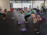 Yoga instructor Mandy DeBord leads Jessica Stephens, in blue, and Alex Gotay, both of Vancouver, during a lunchtime yoga session at Bridge Chiropractic in Salmon Creek. The class is designed so that people can scoot away from work for 50 minutes during their lunch break for a yoga session.