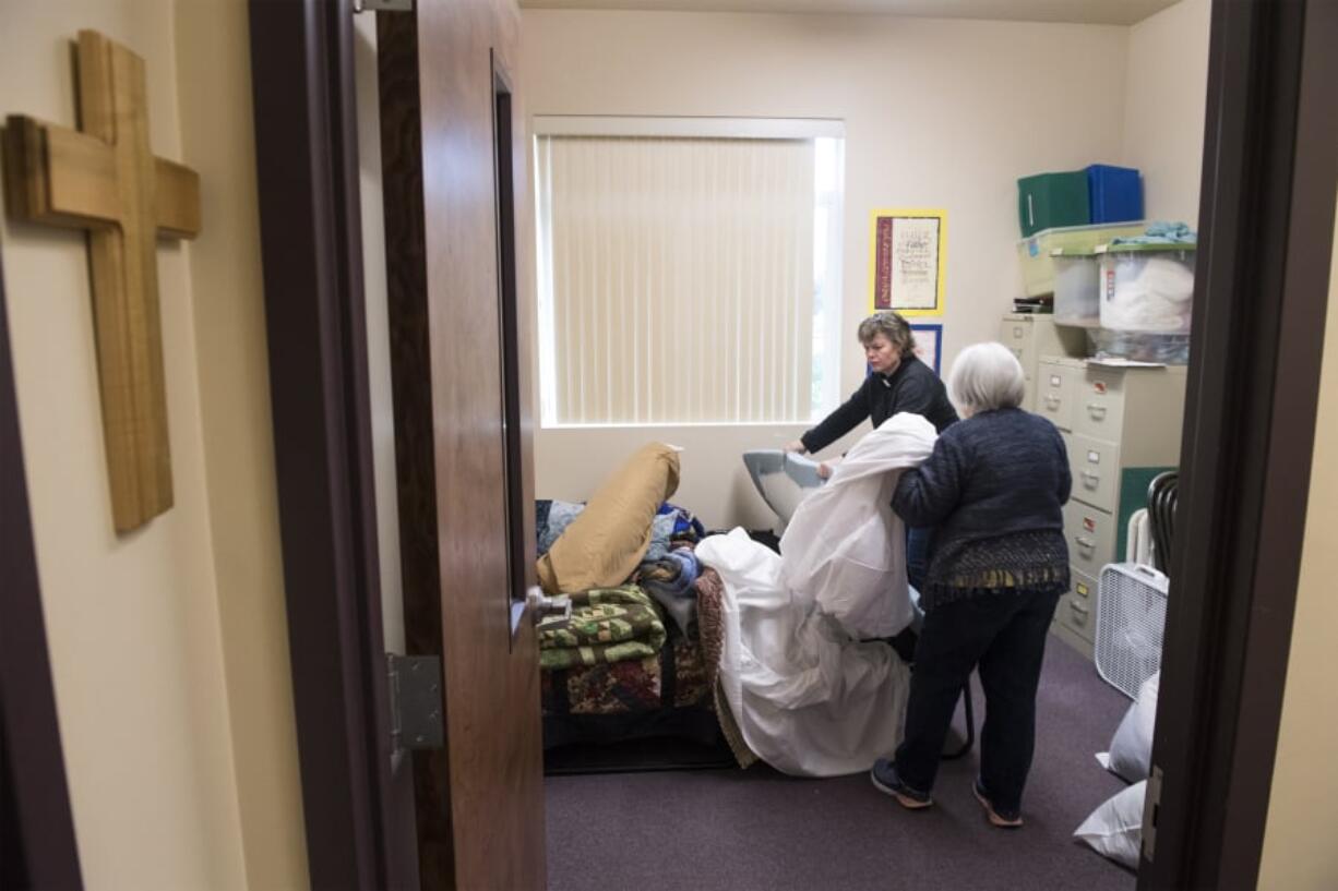 Battle Ground Community United Methodist Church Pastor Susan Boegli, left, and Jean Brown prepare a bedroom for guests arriving Wednesday night. The church is taking a turn hosting Family Promise of Clark County, a new shelter that rotates to a different congregation each week. “Sunday when people come to church this will all be put away,” Brown said.