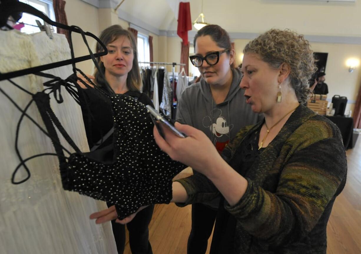 From left, Devaki Chapel, Heidi Blackwelder and Alisa Tetreault eye a piece of clothing Sunday at the Couve Couture marketplace at the Red Cross Building in Vancouver.