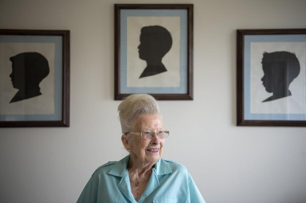 Camas historian Virginia Warren, 94, sits on her bed below three silhouettes she traced and cut out of her sons more than 50 years ago. She recently donated three scrapbooks she compiled of local history to the Camas Public Library.