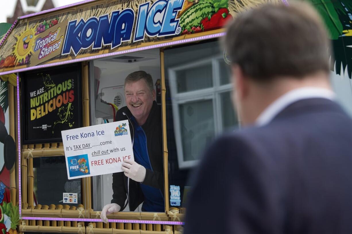 Steve McCulloch of Kona Ice greets pedestrians with a smile as he offers a free shave ice to those passing by the downtown post office Monday afternoon. The event was part of national “Chill Out Day” for those stressed out due to the annual Tax Day deadline.