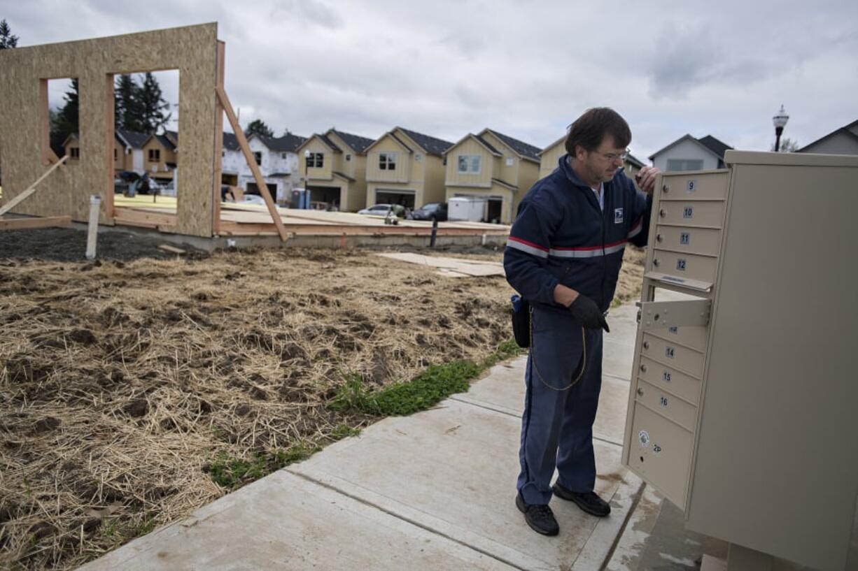 Ed Stanley of the U.S. Postal Service prepares a bank of mailboxes Wednesday at a new Clark County housing development, the Meadows at 58th Street in the Minnehaha area. Clark County’s population growth cycle is continuing at a rate faster than the rest of the Portland metro area.