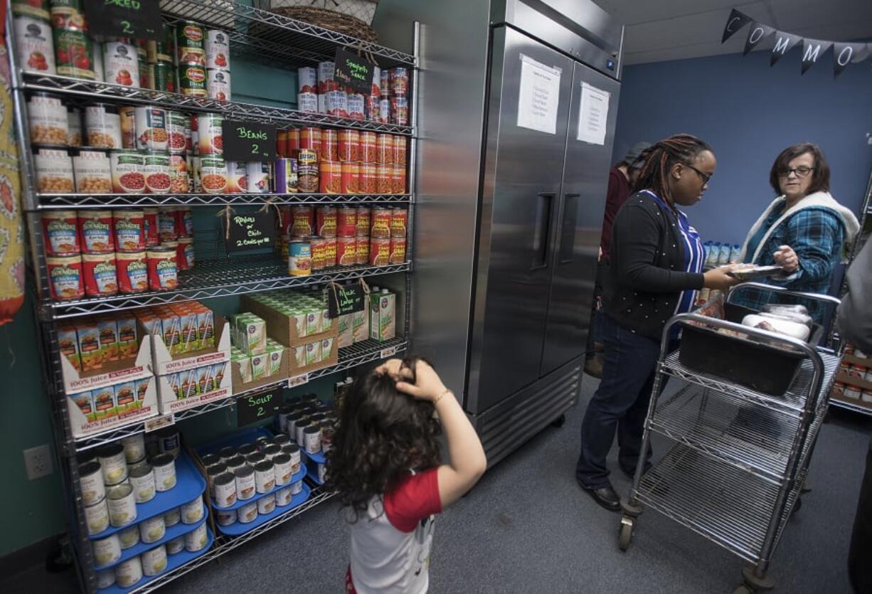 North County Community Food Bank volunteers Damilola Olupona, second from right, and Leona Rider assist clients as they shop for groceries Thursday afternoon. The North County Community Food Bank is one of the few resources for people who are struggling or who are homeless in Battle Ground. It has more than 300 homeless clients.