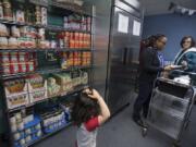 North County Community Food Bank volunteers Damilola Olupona, second from right, and Leona Rider assist clients as they shop for groceries Thursday afternoon. The North County Community Food Bank is one of the few resources for people who are struggling or who are homeless in Battle Ground. It has more than 300 homeless clients.