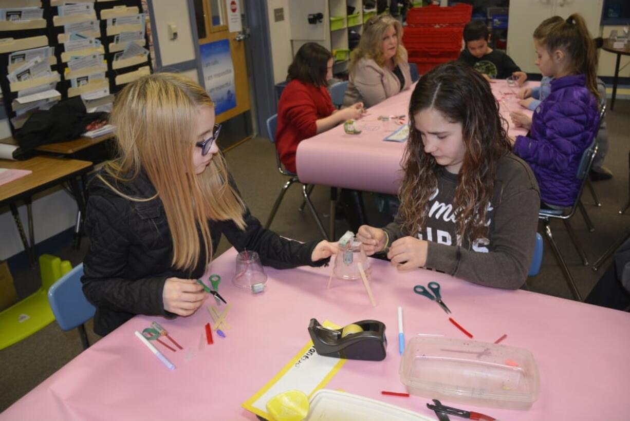 Washougal: Gause Elementary School fourth-graders Vanessa Barela, left, and Keilene Brown work on their scribble bots, which are robots the students were asked to build to scribble onto paper.