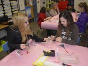 Washougal: Gause Elementary School fourth-graders Vanessa Barela, left, and Keilene Brown work on their scribble bots, which are robots the students were asked to build to scribble onto paper.