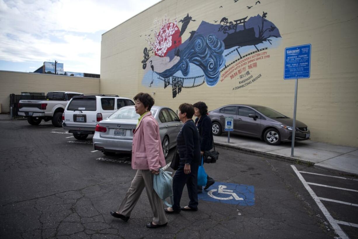 Elko Arakawa, left, Tsuyako Shibata and Tomoe Fujimoto, right, visit a new mural on the back of Kiggins Theatre that celebrates the friendship between Vancouver and their hometown of Joyo, Japan. At top, a close-up of the mural, by Washougal artist Cimarron Brodie.