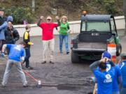 Colin Fogarty, executive director of Confluence, center, cheers on volunteers moving the last bits of a mulch pile.