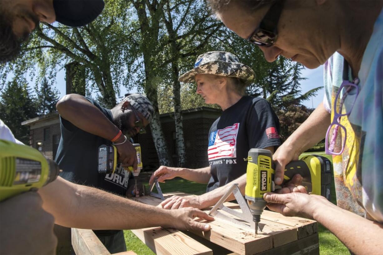 Joshua Franklin, left, Kwame Bey, Tess Acosta, and Debbie Debozy construct a wash and pack station as part of the Boots 2 Roots PDX program on the Vancouver VA Campus.